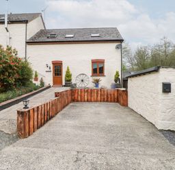 A driveway and entrance area with a white building and wooden door at Mill Barn Denant in Haverfordwest Pembrokeshire