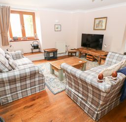 A living room with plaid sofas wooden coffee table and television at Mill Barn Denant in Haverfordwest Pembrokeshire