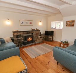 A living room with a fireplace and sofas at Little Barn Cottage in Dinas Cross, Pembrokeshire
