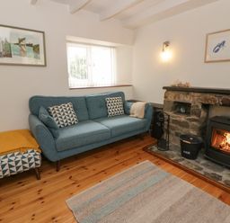 A living room with a sofa and fireplace at Little Barn Cottage in Dinas Cross, Pembrokeshire