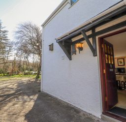 The exterior of a house with an open door showing a dining area inside at Meadowlands in Dinas Cross Pembrokeshire