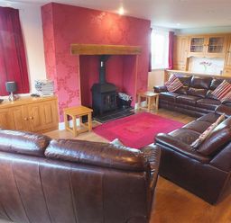 A living room with leather sofas a wood burner and wooden cabinets at Sarnau in Efailwen Carmarthenshire