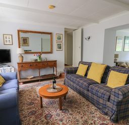 A living room with two sofas a wooden coffee table and a TV on a stand at Yr Odyn in Llangrannog Ceredigion