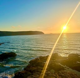 A sunset over the ocean with rocky shore at Beach Cottage in Little Haven, Pembrokeshire
