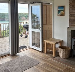 A living room with a table and a view at Beach Cove in Freshwater East, Pembrokeshire