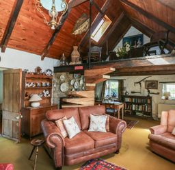 A living room with wooden staircase shelves and seating at Ty-Newydd Cottage in Nevern near Newport Pembrokeshire