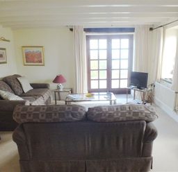 A living room with brown sofas a glass coffee table a television and French doors at Cockshead Cottage St Dogmaels Pembrokeshire