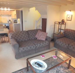 A living room with two sofas a glass coffee table and an open kitchen and dining area at Cockshead Cottage in St Dogmaels Pembrokeshire