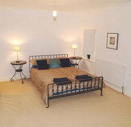 A bedroom with a bed side tables with lamps and stairs on the side at Stable Cottage Cardigan