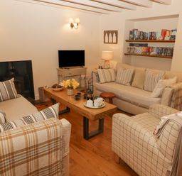 A living room with sofas a wooden coffee table a television and shelves with books at 1 Cheriton Row in Carew Cheriton Nr Tenby Pembrokeshire