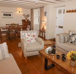 A living room with wooden dining table chairs armchairs a sofa coffee table and a lamp at 1 Cheriton Row Carew Cheriton Nr Tenby Pembrokeshire