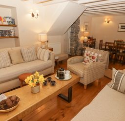 A living room with couches a wooden coffee table bookshelves and a dining table at 1 Cheriton Row Carew Cheriton Nr Tenby Pembrokeshire