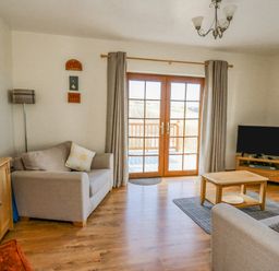 A living room with two sofas coffee table television and wooden cabinet at Beudy in Mwnt Cardigan Ceredigion