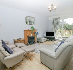 A living room with leather sofas a fireplace a television and large windows at 9 Manorcombe Bungalows St Ann's Chapel near Callington
