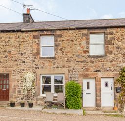 Stone terraced houses with doors and windows with potted plants and a bench outside at Peth Head Cottage in Wooler