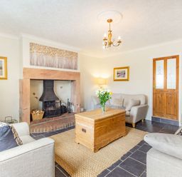 A living room with a fireplace wooden chest coffee table and sofas at Peth Head Cottage in Wooler