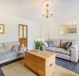 A living room with two beige sofas a wooden chest table and a chandelier at Peth Head Cottage in Wooler