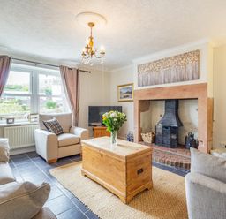 A living room with sofas a wooden chest coffee table a fireplace and a television at Peth Head Cottage in Wooler