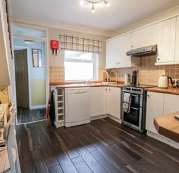 A kitchen with white cabinets wooden countertops and dining table at Scarborough Cottage in Driffield