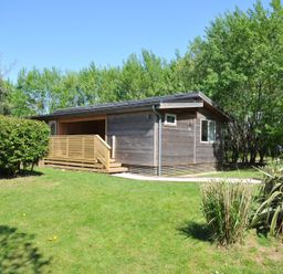 A wooden building with a deck in a grassy area at The Hideout in Lanreath