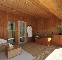 An outdoor area with a wooden bathtub and seating at The Hideout in Lanreath
