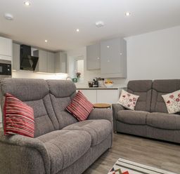 A living room with two gray sofas and a modern kitchen in the background at Flat 2 38 Preston Road in Weymouth