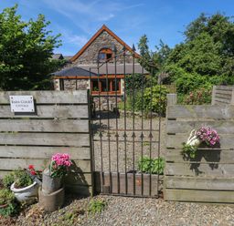 An entrance with a gate and flowers at Barn Court Cottage Narberth, Pembrokeshire