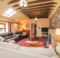 A living room with sofas tables a television and stone fireplace at Stoney Cottage in Narberth Pembrokeshire