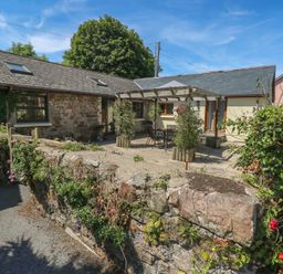 An outdoor patio area with a stone wall and cottage at Stoney Cottage in Narberth, Pembrokeshire