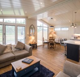 An open plan living room and kitchen with a sofa table chairs and kitchen island at Wren Lodge in Gargrave