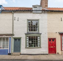 A street view showing a row of old brick buildings with a green door and windows in the center at 48 High Street Bridlington