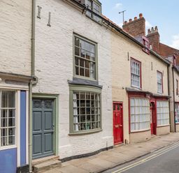 A street view of brick buildings with painted doors and windows at 48 High Street in Bridlington