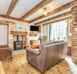 A living room with exposed wooden beams a fireplace a brown armchair and a leather sofa at 48 High Street in Bridlington