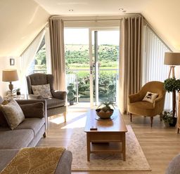 A living room with a sofa, armchair, and coffee table at Larchwood Lodge in Ellon