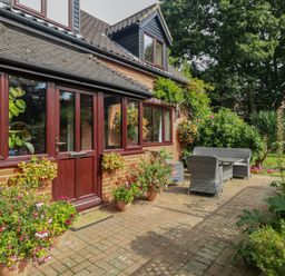 A patio with outdoor furniture and potted plants outside a brick house at Walnut Tree Cottage in Catfield
