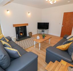 A living room with two dark sofas a wooden coffee table a fireplace and a television at Berth in Afonwen near Criccieth