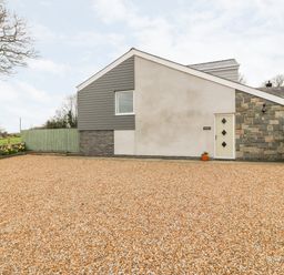 An exterior view of a house with a gravel driveway and a small potted plant by the door at Berth in Afonwen near Criccieth