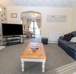 A living room with a blue sofa wooden coffee table a television and a view to dining area at Rhiangwyn in Llanrhyddlad near Cemaes Bay