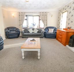 A living room with three armchairs a sofa coffee table and a wooden cabinet at Rhiangwyn in Llanrhyddlad near Cemaes Bay