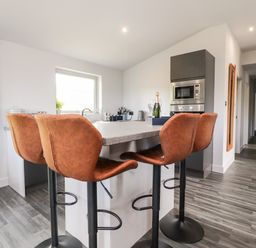 A kitchen with a countertop and four brown bar stools near a microwave at Box Tree Escapes in Wennington near Kirkby Lonsdale