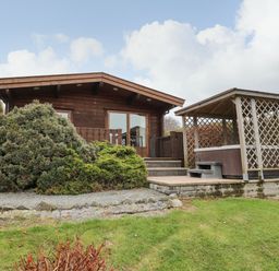 A wooden cabin with a porch and a gazebo on a grassy lawn at Valley View in Rhayader