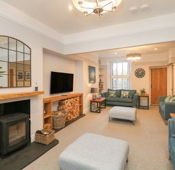 A living room with sofas a TV wood stove and a large mirror at Hazelnut Cottage in Windermere