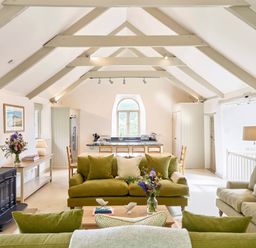 A living room with green sofas wooden table and a black wood stove at Garden House in Cornworthy