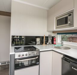 A kitchen with a stove oven microwave sink and refrigerator at Cabin at the Tavern in Coupar Angus