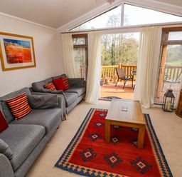 A living room with two grey sofas and a wooden coffee table on a red patterned rug at Jules @ 79 in Stepaside