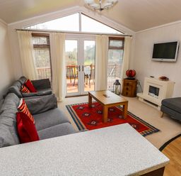 A living room with gray sofas and red pillows a wooden coffee table and a red patterned rug at Jules @ 79 in Stepaside