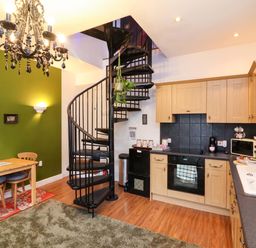 A kitchen with spiral staircase and dining table at The Coach House, The Grove in Combe Martin