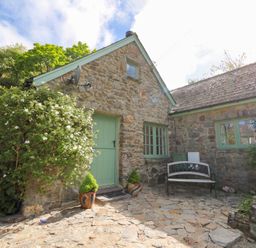 Stone house exterior with green door and windows a bench and some potted plants at Glyn Yr Efail Moylegrove nr Newport and Cardigan