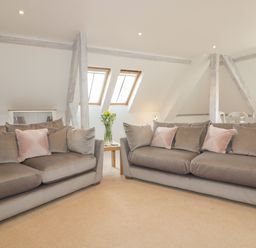 A living room with two gray sofas and pink pillows near windows at Stores & Supplies Bodmin