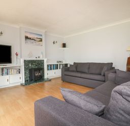 A living room with two grey sofas a television and a fireplace at Three Jays in Lanreath